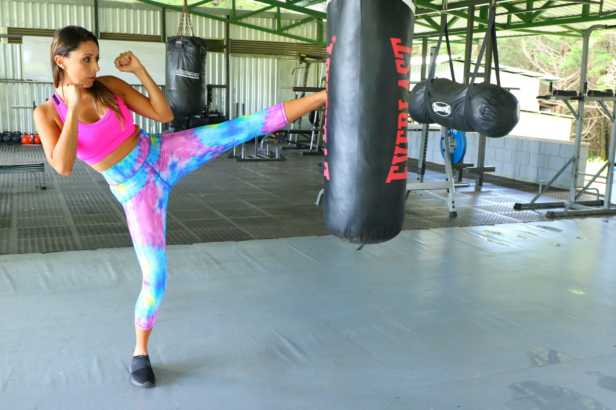 Frau beim Kickboxen mit hohem Kick am Sandsack