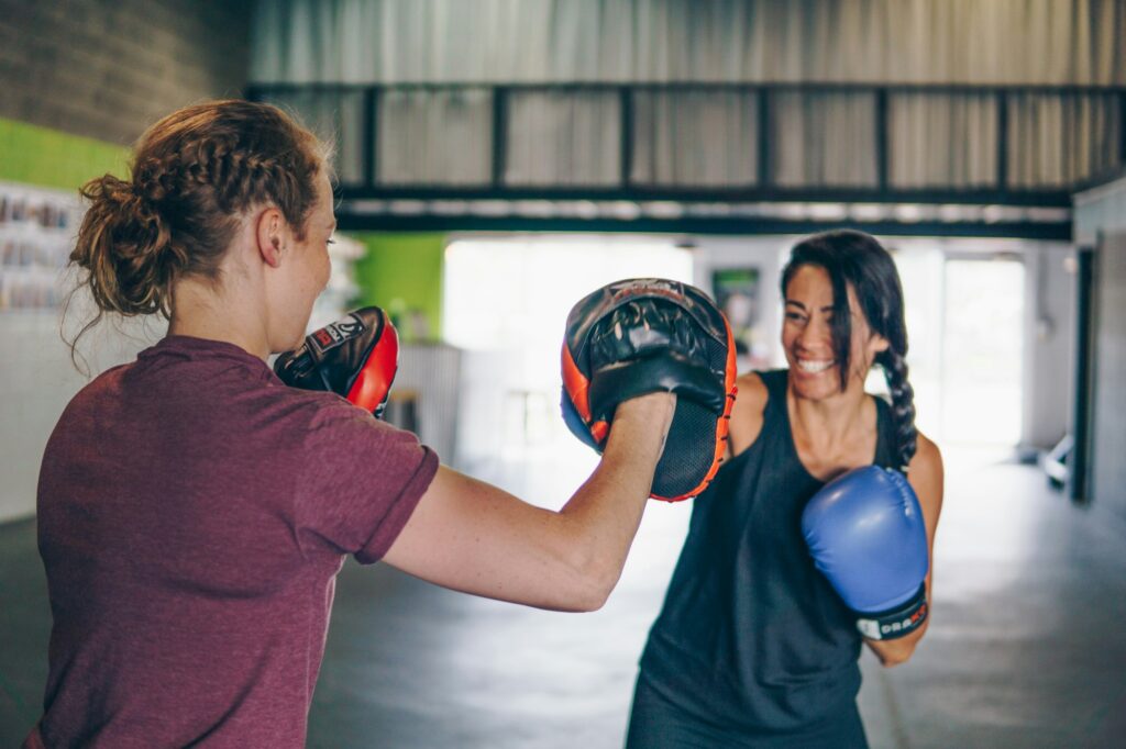 Zwei Frauen beim Partnertraining mit Pratzen und Boxhandschuhen